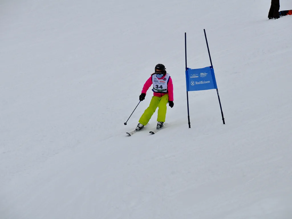 Skifahrerin in gelber Hose neben dem blauen Tor.